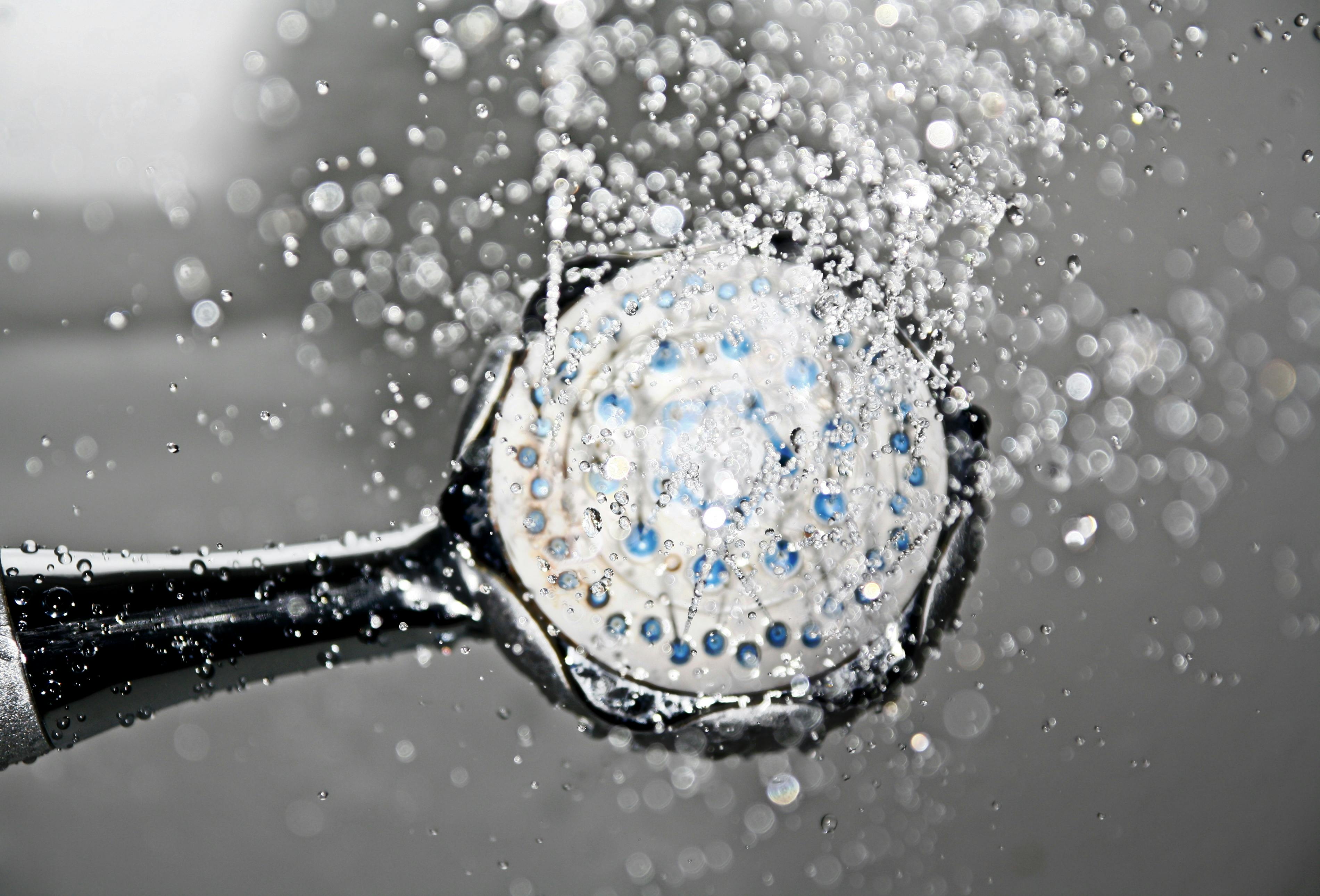 Duschkopf mit laufendem Wasser und feinen Tropfen in der Luft